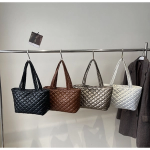 Close-up of quilted tote bags in four metallic colors hanging on a display rack