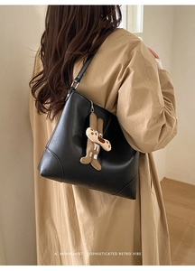 Minimalist black faux leather tote bag with a cute plush dog pendant on shoulder