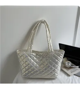 Detailed close-up of a silver quilted tote bag with metallic finish on a white desk