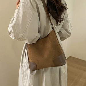 Detail view of a large brown suede tote bag worn by a model for a vintage aesthetic