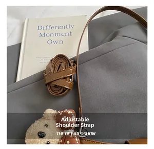 Detail of adjustable brown leather strap featuring a cute plush bear charm with polka dot bow