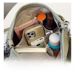Layout interno con ampi scomparti della borsa intrecciata verde con oggetti di uso quotidiano