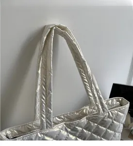 Close-up of quilted silver tote bag handles with metallic finish and rhombic stitching