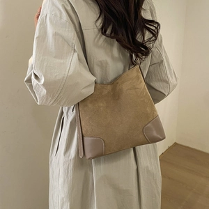 Detail view of a khaki matte suede bucket bag with leather corners and contrast stitching