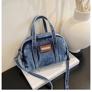 Close-up of vintage blue denim handbag with brown leather accents and metal hardware
