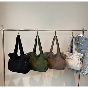Large corduroy tote bags for women in four solid colors hanging on a metal rack