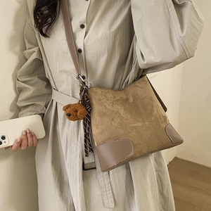 Detail of vintage brown frosted bucket bag with leather reinforced corners and bear charm