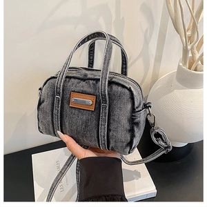 Close-up of a vintage washed denim handbag with brown leather accent and top handles