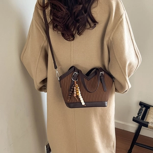 Detail der braunen Vintage-Beuteltasche mit Faltenstruktur und schickem Holzperlenanhänger