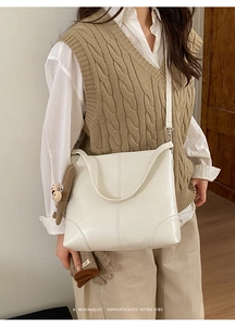 Detailaufnahme der weißen Kunstleder-Tote Bag mit braunem Bärenanhänger und langem Gurt