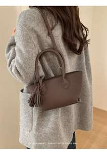 Detail of dark brown minimalist tote bag with tassel pendant and crossbody strap