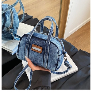 Detail of washed blue denim handbag with leather accent and adjustable shoulder strap