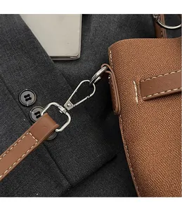 Détail du crochet argenté et coutures blanches sur le sac en cuir litchi marron