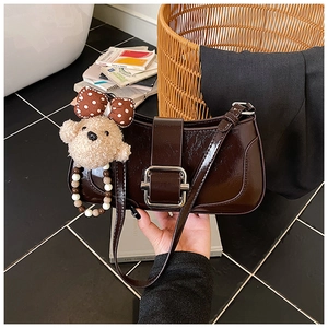 Détail du sac à épaule en cuir verni marron foncé avec boucle argentée et breloque