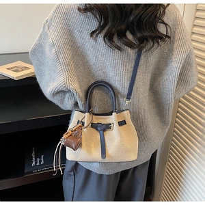 Detail of woven straw bucket bag with blue leather straps and vintage metallic buckle