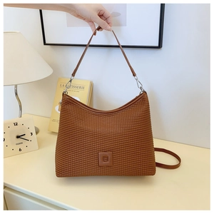 Dettaglio di una borsa a tracolla marrone plissettata con texture fine e logo quadrato