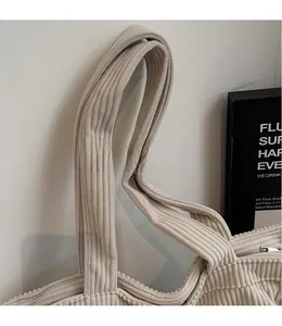 Detailed macro view of wide shoulder strap and corduroy texture on beige tote bag