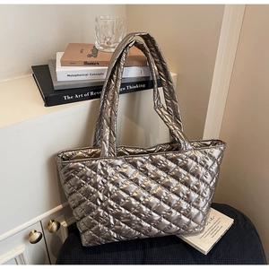 Detail of metallic bronze quilted tote bag with large diamond stitching and wide strap