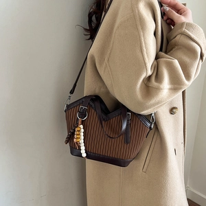 Details der dunkelbraunen Falten-Beuteltasche mit Holzperlenquaste auf einem Wollmantel