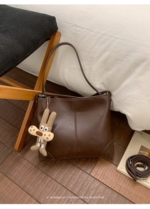 Detail of dark brown tote bag showing smooth PU leather texture and plush rabbit charm