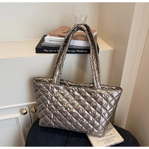 Detailed view of champagne quilted tote bag with metallic finish and long top handles
