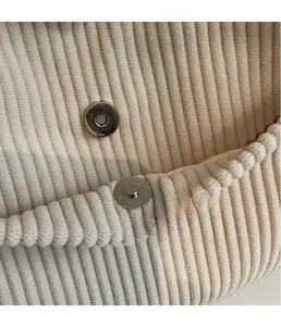 Macro shot of circular metal magnetic closure on wide-ribbed velvet corduroy tote bag