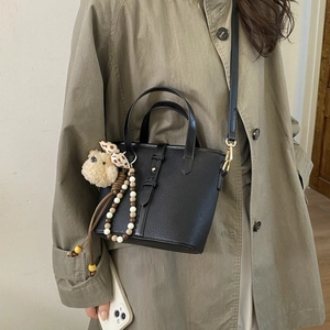 Detail of black lychee grain bucket bag with teddy bear charm and beaded tassel