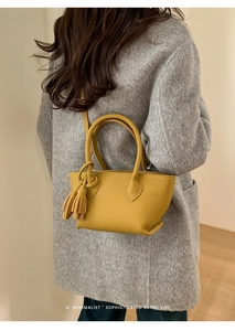 Detailed back view of a yellow lychee pattern handbag paired with a grey textured coat