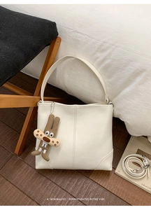 Detail of off-white leather tote bag showing fine vertical stitching and detachable strap