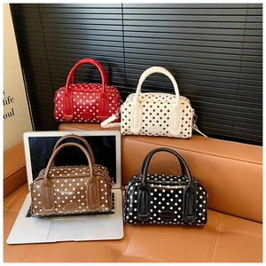 Detailed close-up of colorful polka dot cylinder pillow bags with metallic zippers