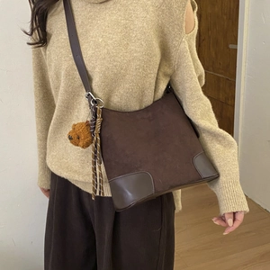 Detail of dark brown matte suede bucket bag with leather base and cute bear charm