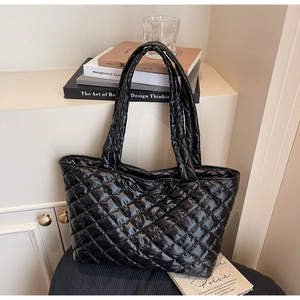 Macro detail of large quilted rhombus pattern on a black glossy nylon tote bag