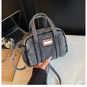 Close-up of vintage washed denim boston bag on desk with laptop and headphones