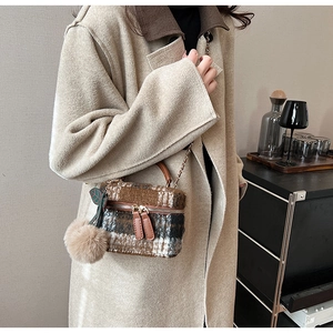 Detail van tweed geruite mini box tas met pluche pompon en ketting schouderband