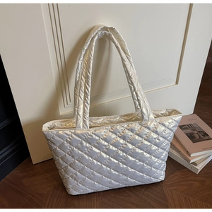 Detail shot of a quilted tote bag featuring a glossy pearl white finish and padded handles