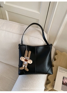 Detail of black large faux leather tote bag with stylish long plush bunny keychain accessory