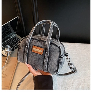 Detailed view of the small denim crossbody bag with vintage washed texture and leather accents