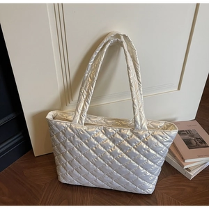 Detail of white quilted puffer tote bag with glossy finish and wide shoulder straps