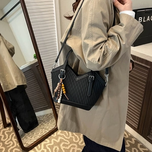 Detail einer schwarzen Falten-Beuteltasche mit Vintage-Struktur und Holzperlen-Anhänger