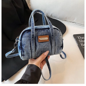 Close-up of distressed blue denim tote bag with brown leather patch and dual handles