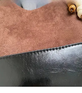 Close-up of retro brown frosted suede and black patent leather stitching on tote bag