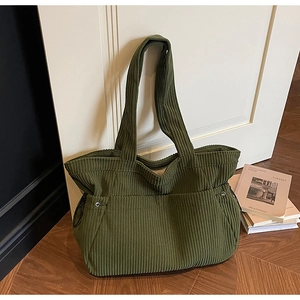 Detailed view of dark green corduroy tote bag showing vertical ribbed texture and metal eyelets