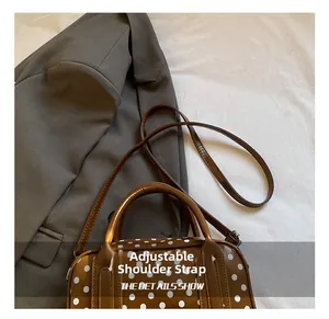 Close-up of brown polka dot boston bag featuring adjustable thin shoulder strap