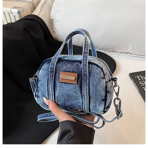 Detail of vintage washed denim handbag with brown leather tag and metal buckle