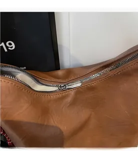 Detailed close-up of smooth metal zipper closure on brown vintage leather tote bag