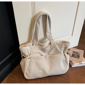 Detail view of cream corduroy tote bag featuring adjustable black drawstring and toggle