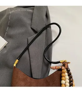 Detail of suede tote bag with elegant wooden bead tassels and black slender strap