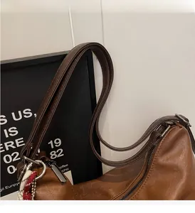 Detailed close-up of brown textured leather tote with silver metal rings and zipper