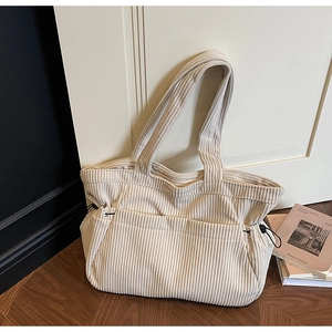 Detail of beige corduroy tote bag showing ribbed texture and side drawstring toggles
