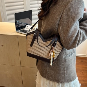 Details der beige gefalteten Beuteltasche mit Lederbesatz und modischem Holzperlenanhänger